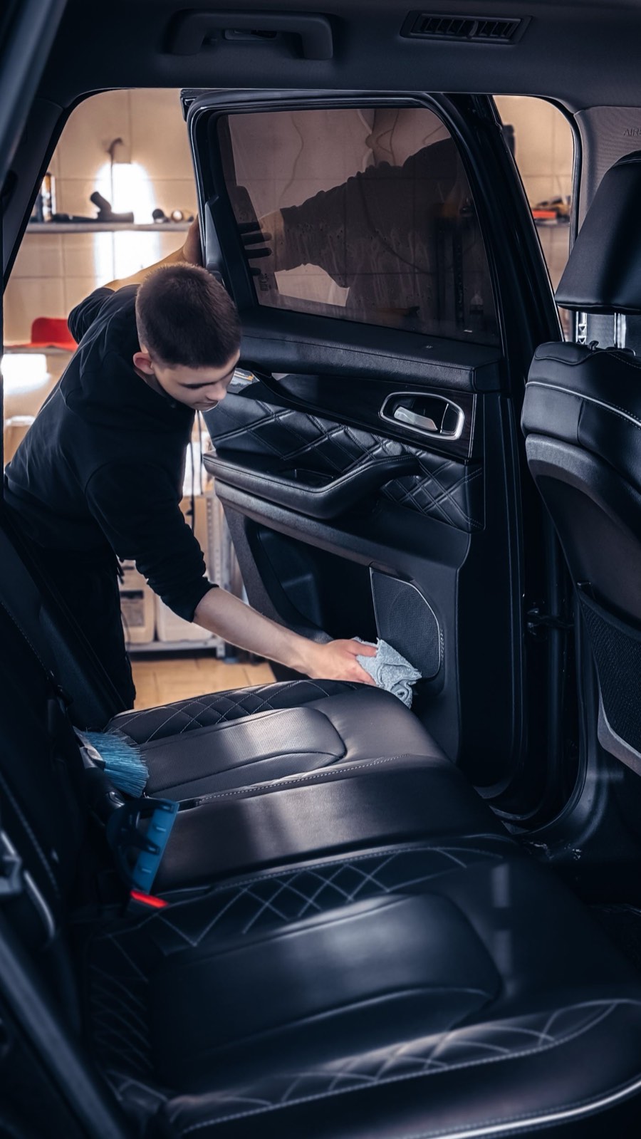 Detailer wiping down the leather rear seats of an SUV